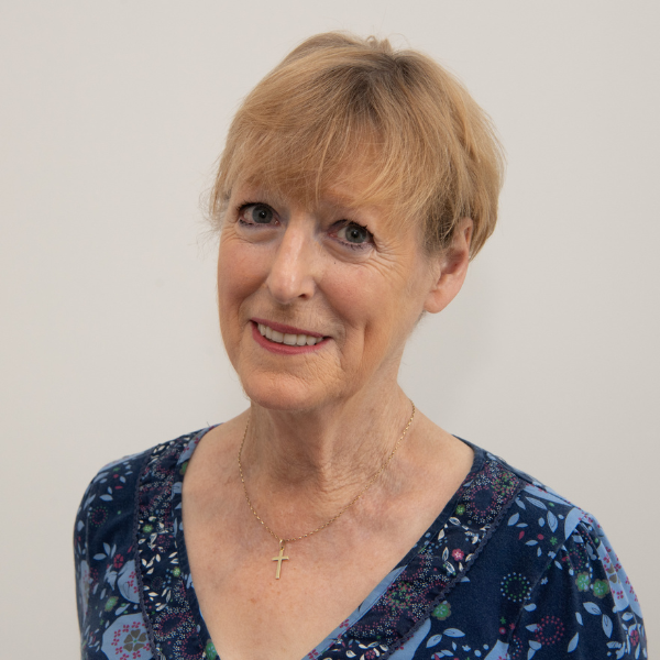 Headshot of a white older woman with short blond hair and a V-neck blue top